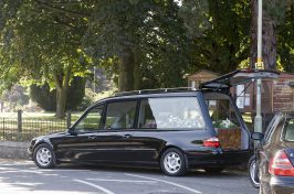 Black hearse with coffin and floral tributes